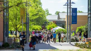 a shot of people attending picnic day at the RMI grounds, with RMI buildings in background.